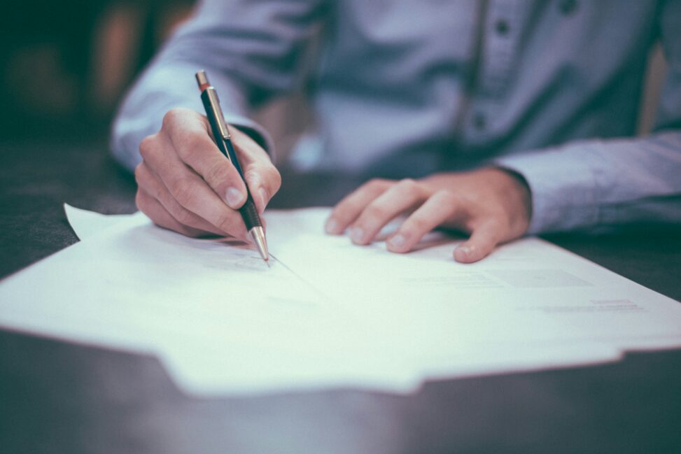 Hand writing notes on paper with a pen.
